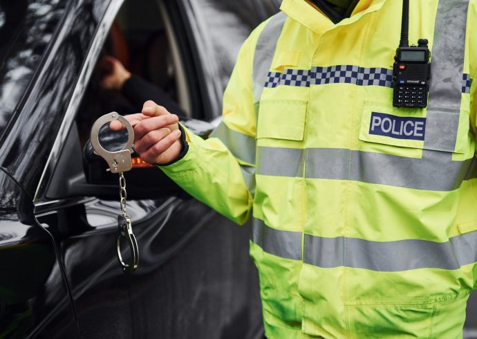 male-police-officer-in-green-uniformstanding-with-handcuffs-near-automobile.jpg